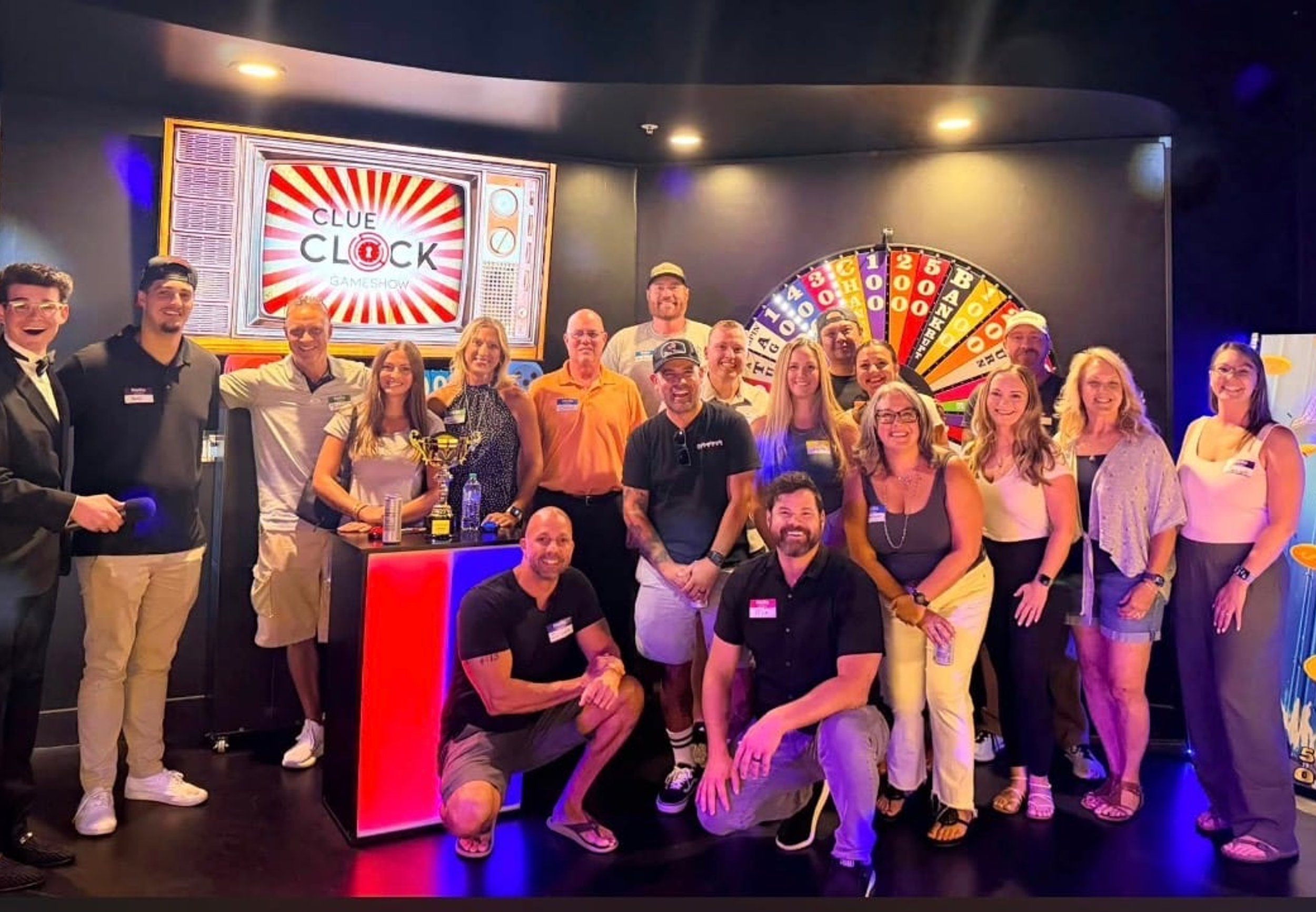 Large group celebrating with their host during a live game show at ClueClock Gameshow in Castle Pines